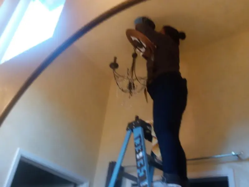 Electrician installing a chandelier in a Downey residence